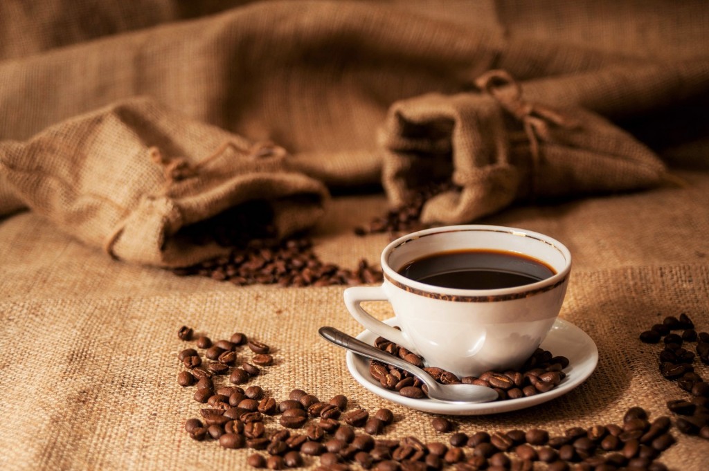 Cup of cowboy coffee with burlap bags of arabica beans